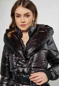 Geacă puf din material negru, cu guler mare, textură lucioasă, design matlasat și talie încinsă. Se închide cu nasturi vizibili și fermoar.