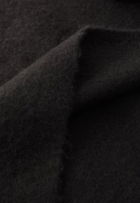 Must have villaneelisest kangast pehme ja karvane tekstuur, näidates voltide ja kergete varjude erinevusi. Pind näib paks ja tihe.