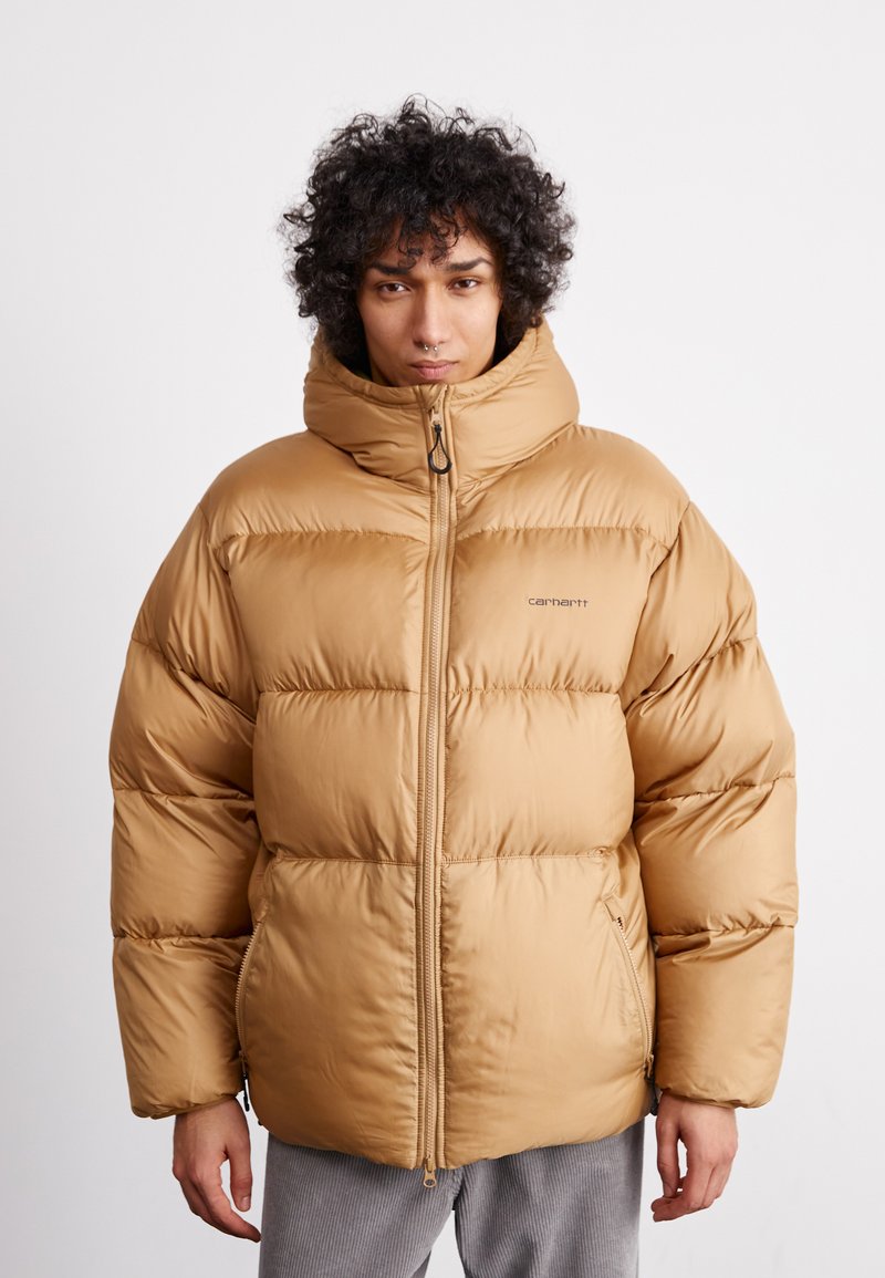 Beige pufferjakke med høj krave, lynlås og quiltet design. Har en glat, blank overflade og sidelommer.