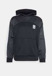 Sweat à capuche noir avec une texture lisse, présentant des accents blancs sur les côtés et un petit écusson logo sur le devant. Poche kangourou à la taille.