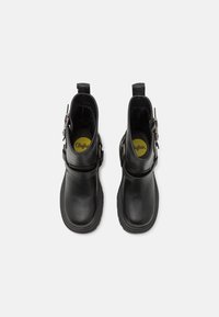 Black leather ankle boots with a smooth texture, rounded toes, adjustable strap hardware, and yellow insoles. Top-down view.