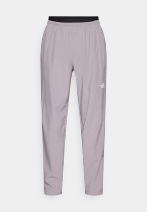 Lys lilla treningsbukser med elastisk midjebånd og smale ben. Har en logo på nedre ben og et glatt, lett stoff.