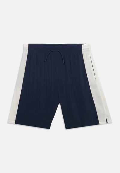 Σορτς σε ναυτικό μπλε με λευκές πλαϊνές λωρίδες, ελαστική μέση, κορδόνι σύσφιξης και πλαϊνές τσέπες, σε ανοιχτό φόντο.