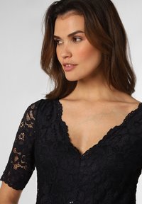 Navy kanttop met een geschulpte V-hals en korte mouwen, met bloemenpatronen en een gestructureerde afwerking.