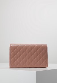 Prošívaná růžová kožená kabelka obdélníkového tvaru, hladké textury a s uzavřením na horním klapce. Vzory jemného švu a elegantní designové akcenty.