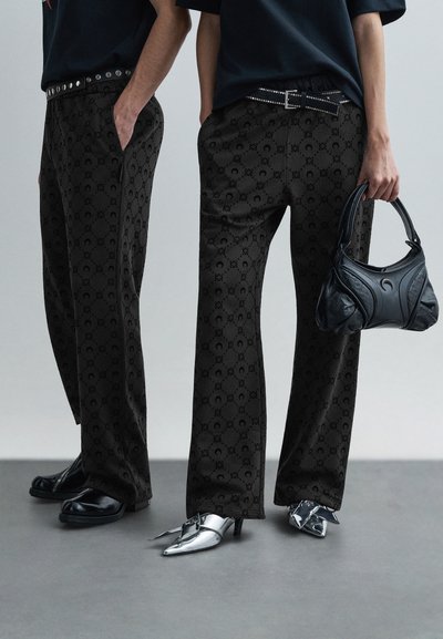 Czarne spodnie wzorzyste o gładkiej fakturze, wyposażone w pasek z srebrnymi ćwiekami. Połączone z kontrastującymi butami w kolorze czarnym i srebrnym.