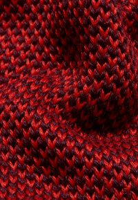 Tessuto lavorato a maglia in tonalità di rosso profondo e bordeaux, caratterizzato da un motivo intrecciato e testurizzato. La superficie appare morbida e spessa.