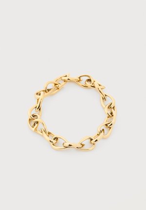 Brățară cu lanț în nuanță aurie, cu zale ovale mari, neregulate, aranjate într-o formă circulară pe un fundal simplu, deschis.