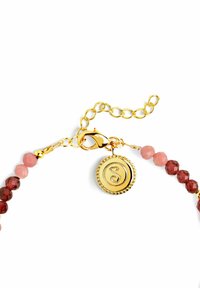 Pulsera de cuentas con piedras opacas en tonos rosa y rojo, cierre en tono dorado con un charm circular grabado con una "S" estilizada.