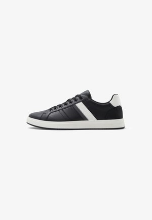 Schwarze Sneakers mit einem strukturierten Leder-Obermaterial, weißen Streifen und einer kontrastierenden weißen Ferse. Sie verfügen über runde Schnürsenkel und eine Gummisohle.