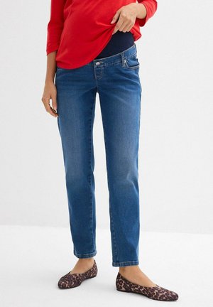 Jeans premaman blu con una vita aderente, design a gamba dritta e leggera scoloritura. Abbinati a un top rosso a maniche lunghe e ballerine con stampa leopardata.