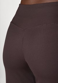 Mørkebrun ribbede leggings med en tætsiddende pasform, der har en høj talje og diskrete syninger langs topseam.