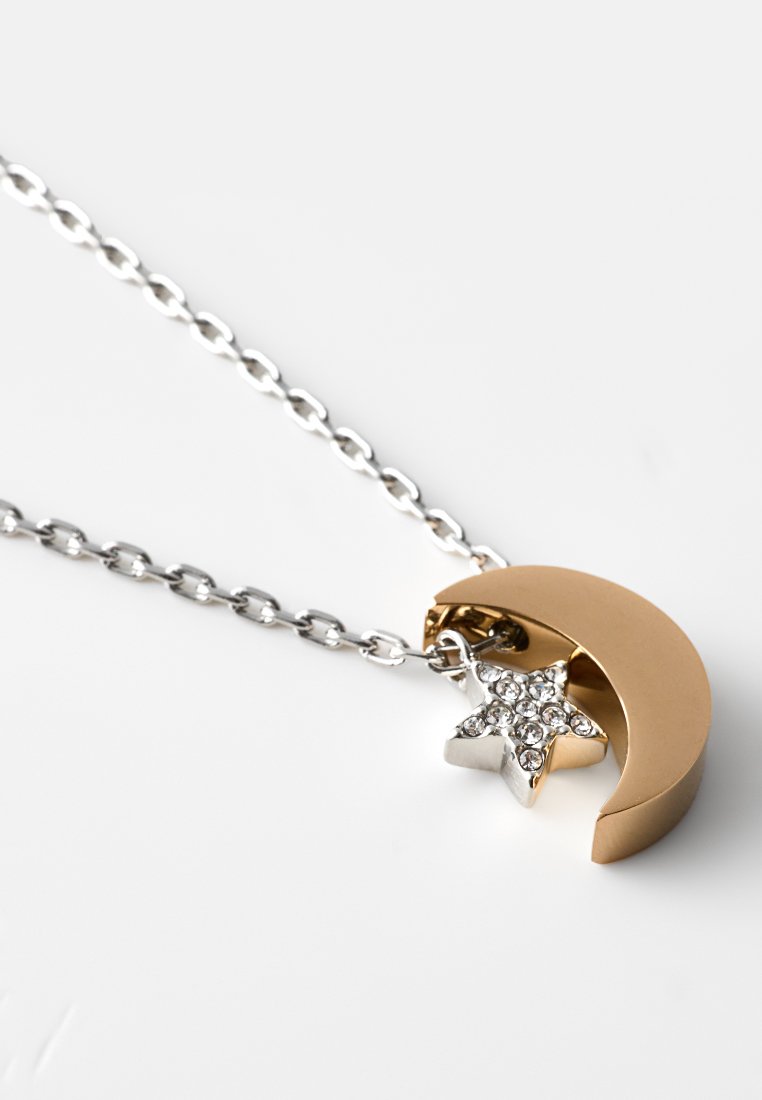 Goldene Halbmondanhänger mit einem silbernen Stern, geschmückt mit klaren Kristallen, an einer silbernen Kette. Polierte Oberfläche, modernes Design.