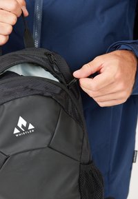 Black backpack with textured fabric, round shape, side mesh pocket, and white logo. Zipper partially open, revealing a light interior.