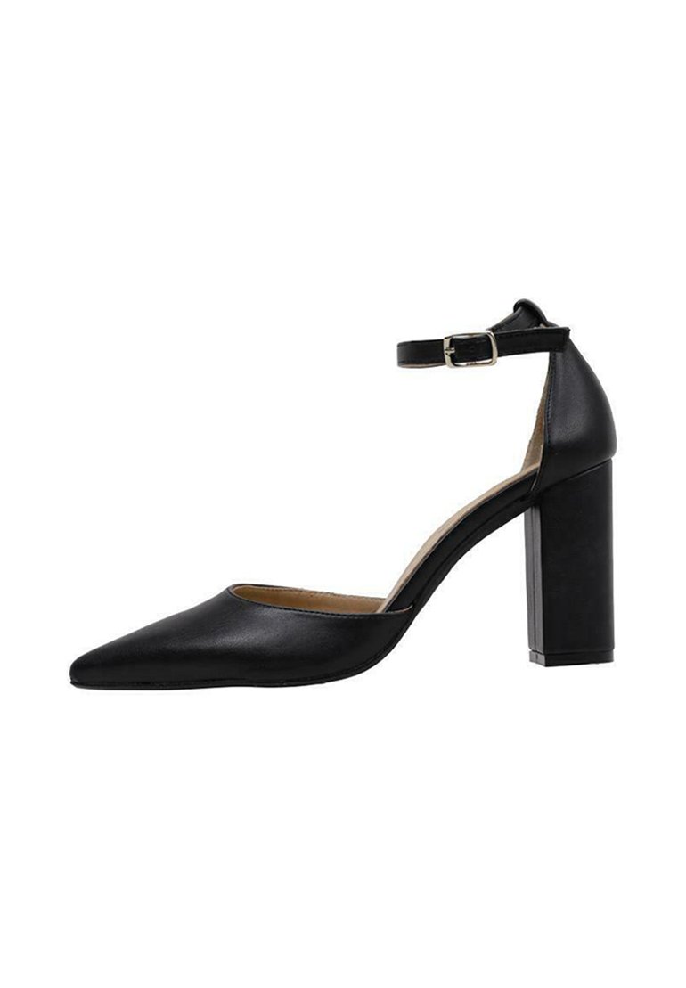 Zapato de tacón alto de cuero negro con punta afilada y correa al tobillo, que presenta un tacón bloque y una textura suave.
