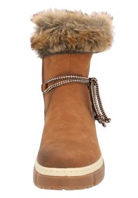 Bota de cuero marrón con ribete de pelo sintético, que presenta una puntera redondeada, suela flexible y cordones decorativos. Diseño texturizado y resistente.