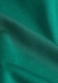 Textiel in donkergroen, met een zachte textuur en subtiele ribbeling, valt soepel en toont een levendige kleur zonder patronen of versieringen.