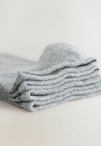 Šedé pletené ponožky uspořádané v řadě, předvádějící jemnou texturu a rovnoměrný ribbový vzor podél okrajů. Materiál vypadá lehký a útulný.