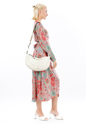 Weißes Lederhandtasche in Halbmondform mit einem abnehmbaren Schulterriemen, präsentiert zusammen mit einem bedruckten Blumenkleid in verschiedenen Rosatönen und Blau.