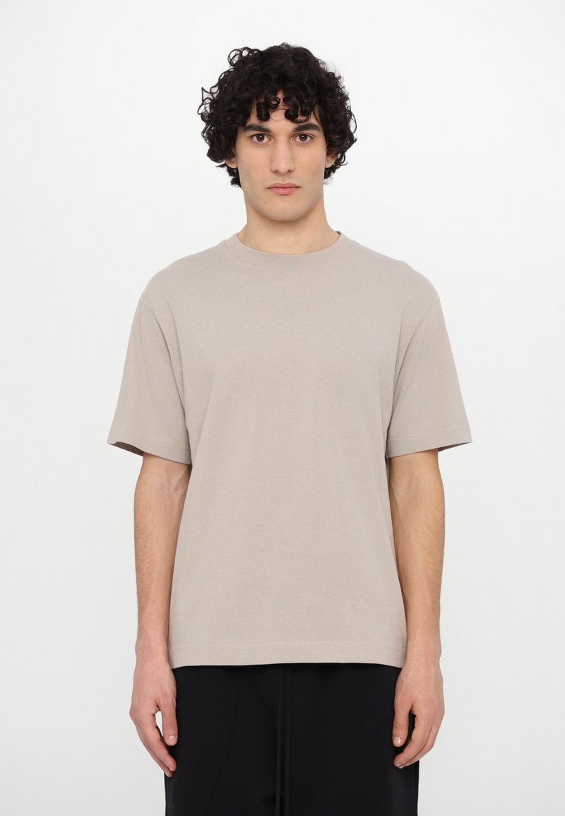 Beige cotton t-shirt with a round neckline, short sleeves, and a relaxed fit. Smooth texture and no visible patterns or accents.