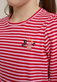 Červeno-růžový pruhovaný krátký rukáv košile s kulatým výstřihem a květinovou výšivkou na levé straně. Měkká bavlněná tkanina.