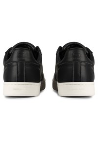 Black leather sneakers with a white rubber sole, featuring a smooth texture, minimalistic design, and embossed logo on the heel.