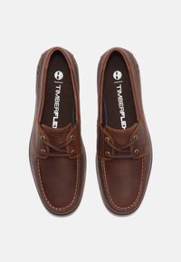 Braune Leder Schuhe mit Schnürdesign, kontrastierenden Nähten, runder Spitze und Logo auf der Innensohle. Glatte Textur mit leichtem Glanz.