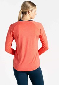 Korallefarbenes, langärmliges Sporthemd mit abgerundetem Saum und einem kontrastierenden navyfarbenen Kragen. Besitzt Raglanärmel und eine glatte Textur.