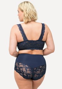 Bralette de encaje azul marino con tirantes anchos de encaje, combinado con braguitas de tiro alto que presentan detalles de encaje y un panel trasero liso.