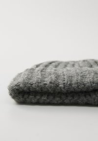 Gray knit beanie with a ribbed texture, featuring a soft wool-like appearance and a folded hem at the base.