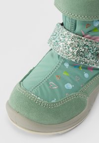 Botas de inverno para crianças em verde menta com uma tira brilhante e padrões de corações e bolhas em rosa e verde no tecido superior.