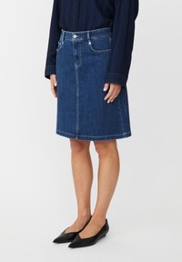 Jupe en denim bleu foncé, longueur au genou, avec cinq poches, une fermeture par bouton et des surpiqûres contrastées le long de l'ourlet.