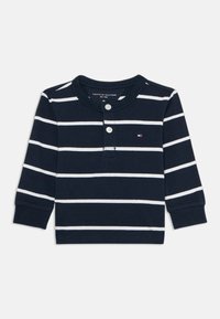 Maglietta a maniche lunghe color navy con strisce bianche, colletto rotondo, patta con due bottoni e piccolo logo sul petto. Materiale in cotone, texture morbida.