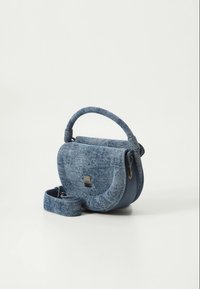 Denim crossbody bag with a rounded shape, textured blue fabric, a solid blue leather base, and a detachable strap. Silver hardware detail.