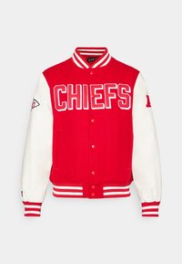Rdeča jakna varsity s belimi usnjenimi rokavi, logotip "CHIEFS" spredaj, prožne črtaste manšete in ovratnik, zapiranje na pritisni gumb ter stranska žepa.