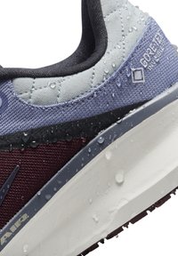 Baskets résistantes à l'eau avec une tige en textile gris et violet présentant un motif matelassé, accentuées par des détails bordeaux et une semelle intermédiaire blanche.