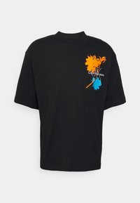 Black cotton T-shirt with a relaxed fit. Features orange and blue graphic designs and "Calvin Klein Jeans" logo on the front.