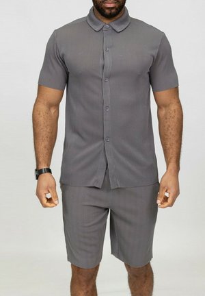 Chemise à manches courtes grise avec des rayures verticales, accompagnée d'un short assorti, le tout en tissu lisse. Comprend un col et des boutons visibles.