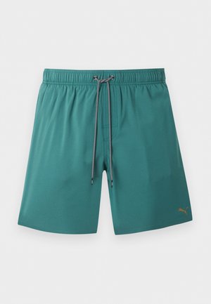 Tyrkysové plavkové šortky s elastickým pásom, čierno-bielym sťahovacím šnúrkou a malým zlatým logom Puma na spodnej pravej nohe.