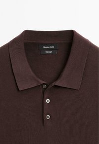 Polo shirt in cotone marrone con una trama texture, tre bottoni e colletto a costine. L'etichetta riporta "Massimo Dutti" con le istruzioni per la cura.