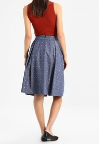 Jeanskjol i A-linje med hög midja, prydd med ett subtilt hjärt-mönster i ljusblått. Lätt tyg, veckad design och knälång.