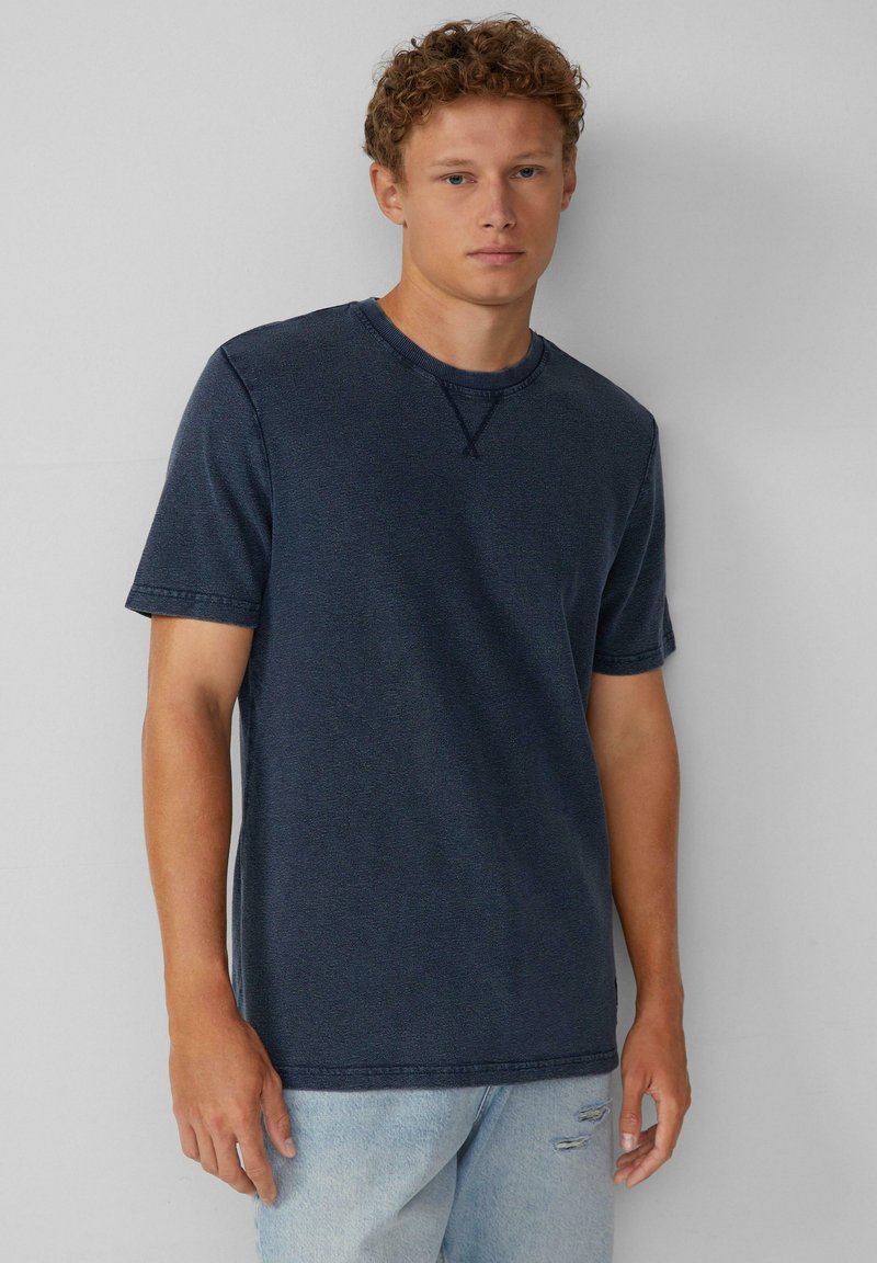 Marineblaues Baumwoll-T-Shirt mit kurzen Ärmeln, Rundhalsausschnitt und strukturierter Oberfläche. Verfügt über dezente Nähte am Ausschnitt.