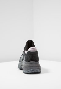 Mustat ja harmaat lenkkarit, joissa on teksturoitu mokkanahka yläosa, pehmustettu nilkkaosa ja paksu kumipohja. Varustettu verkkoyksityiskohdilla ja hillityllä vaaleanpunaisella vivahteella.