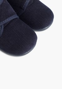 Pantofole in corduroy blu navy con parte superiore testurizzata, fascia elastica sul dorso del piede e suola in gomma per una buona aderenza. Forma della punta arrotondata.