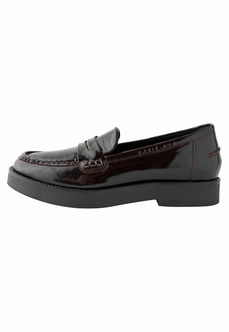 Mocassins en cuir verni bordeaux foncé avec des détails cousus, un bout rond et une épaisse semelle en caoutchouc noir. Talon plat, design classique.