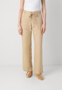 Beige linen wide-leg trousers with a drawstring waist, featuring a textured surface and a relaxed fit, paired with light brown platform shoes.