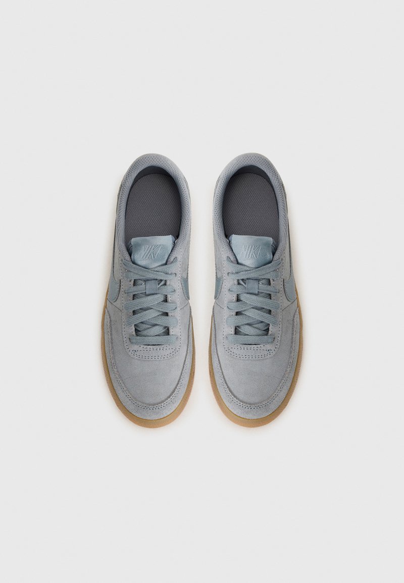 Zapatillas de ante gris claro con cordones grises, suelas de goma y una plantilla texturizada. Logo de Nike embosado en la lengüeta. Vista superior.