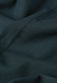 Tessuto verde scuro con una fine trama a coste, che mostra pieghe e ombre. Il materiale appare morbido e leggermente elastico.