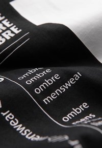 Musta kangas, jossa valkoista tekstiä toistuvat sanat "ombre miesten muoti" eri kokoisina ja suuntiin.