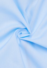 Tessuto azzurro chiaro con una texture liscia, spiegazzato e raccolto al centro, che mostra un motivo di tessitura uniforme in tutto il tessuto.